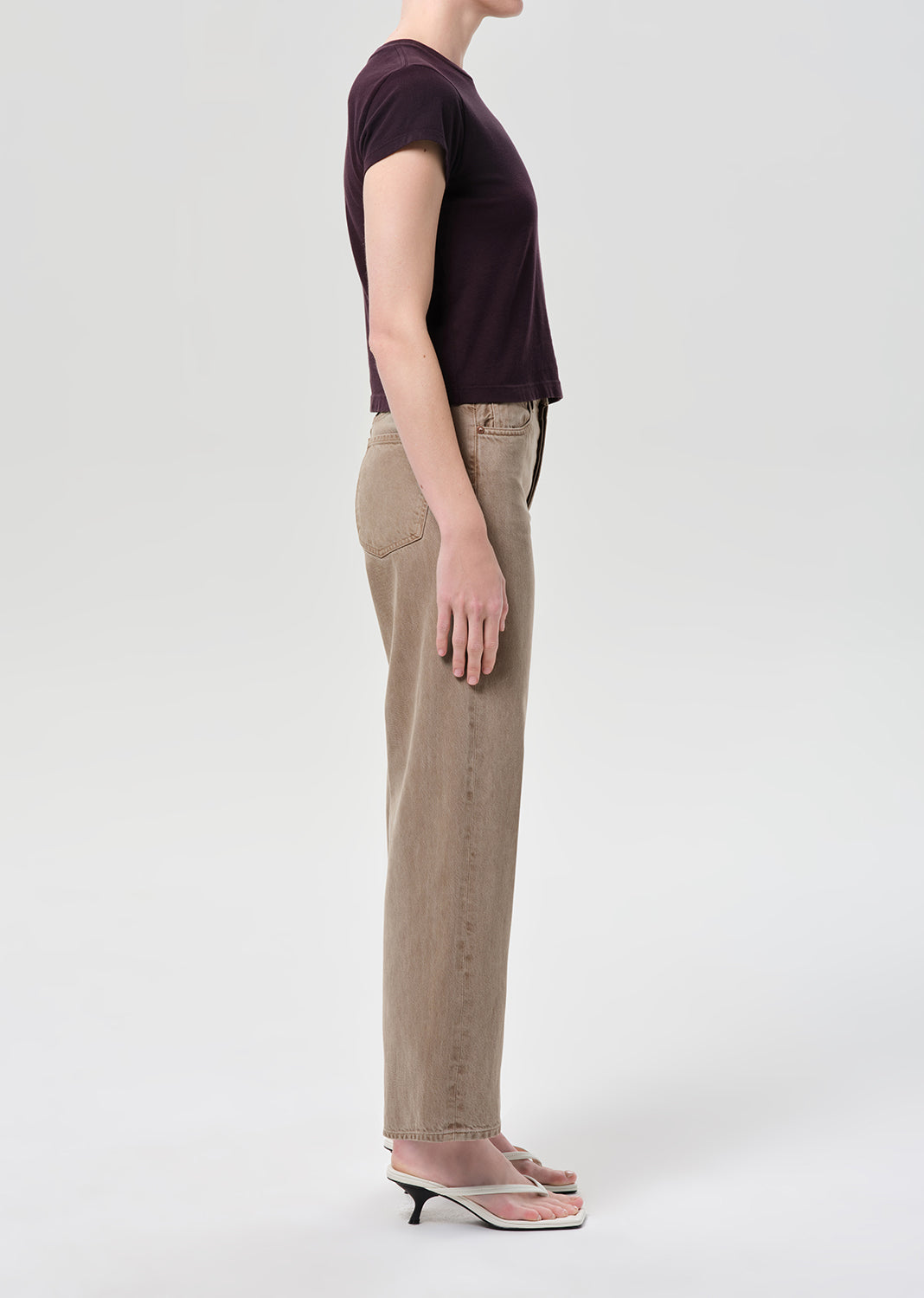 Side shot of person wearing purple top and brown jeans