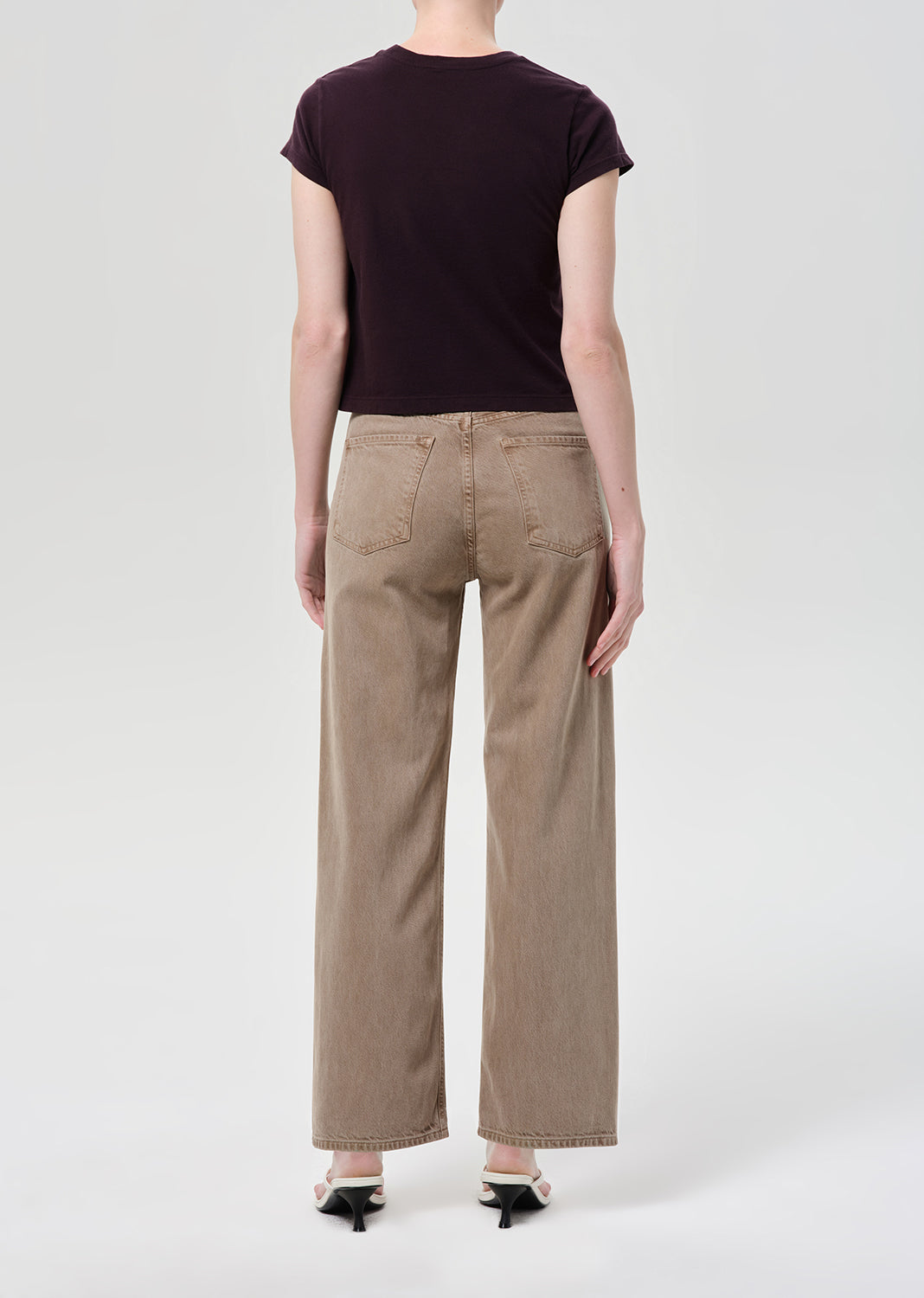 Back shot of person wearing purple top and brown jeans
