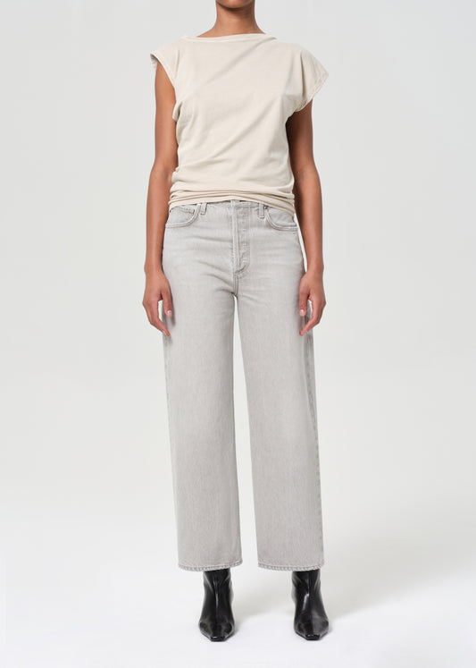 Person wearing a beige top and light gray jeans on a white background