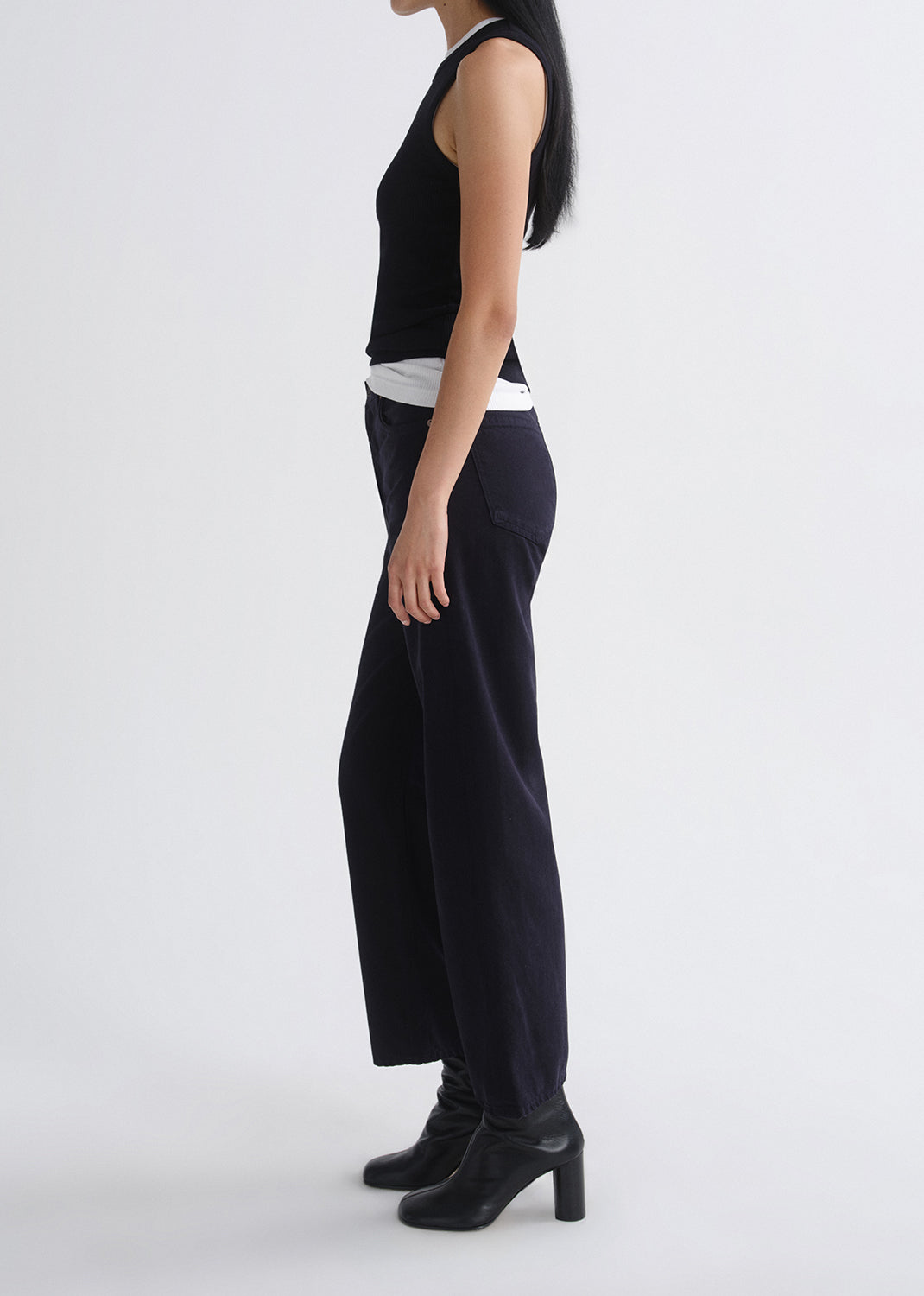 Person wearing a layered black tank and black pants on a grey background