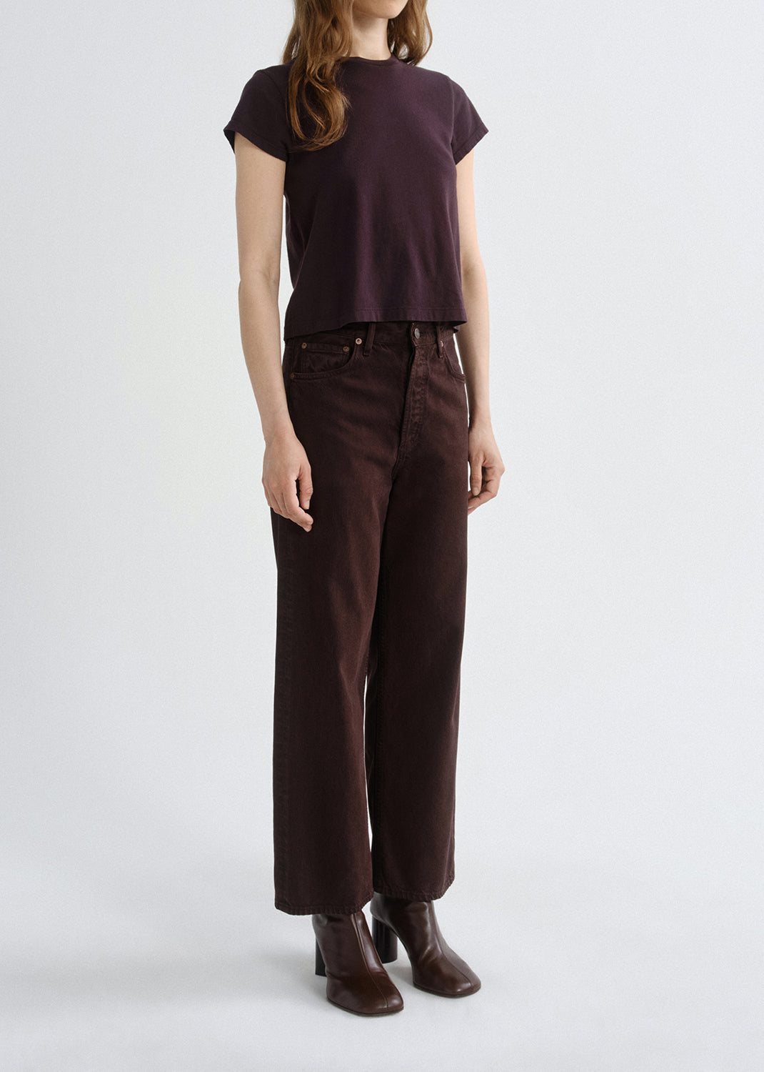 Person wearing a brown t-shirt and pants on a grey background