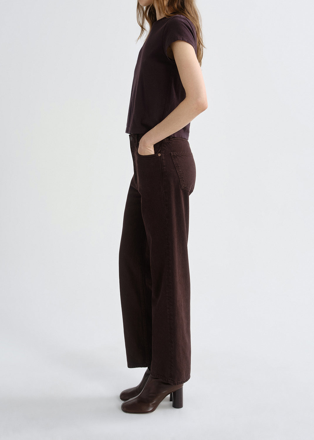Person wearing a dark brown outfit with wide-leg pants on a grey background