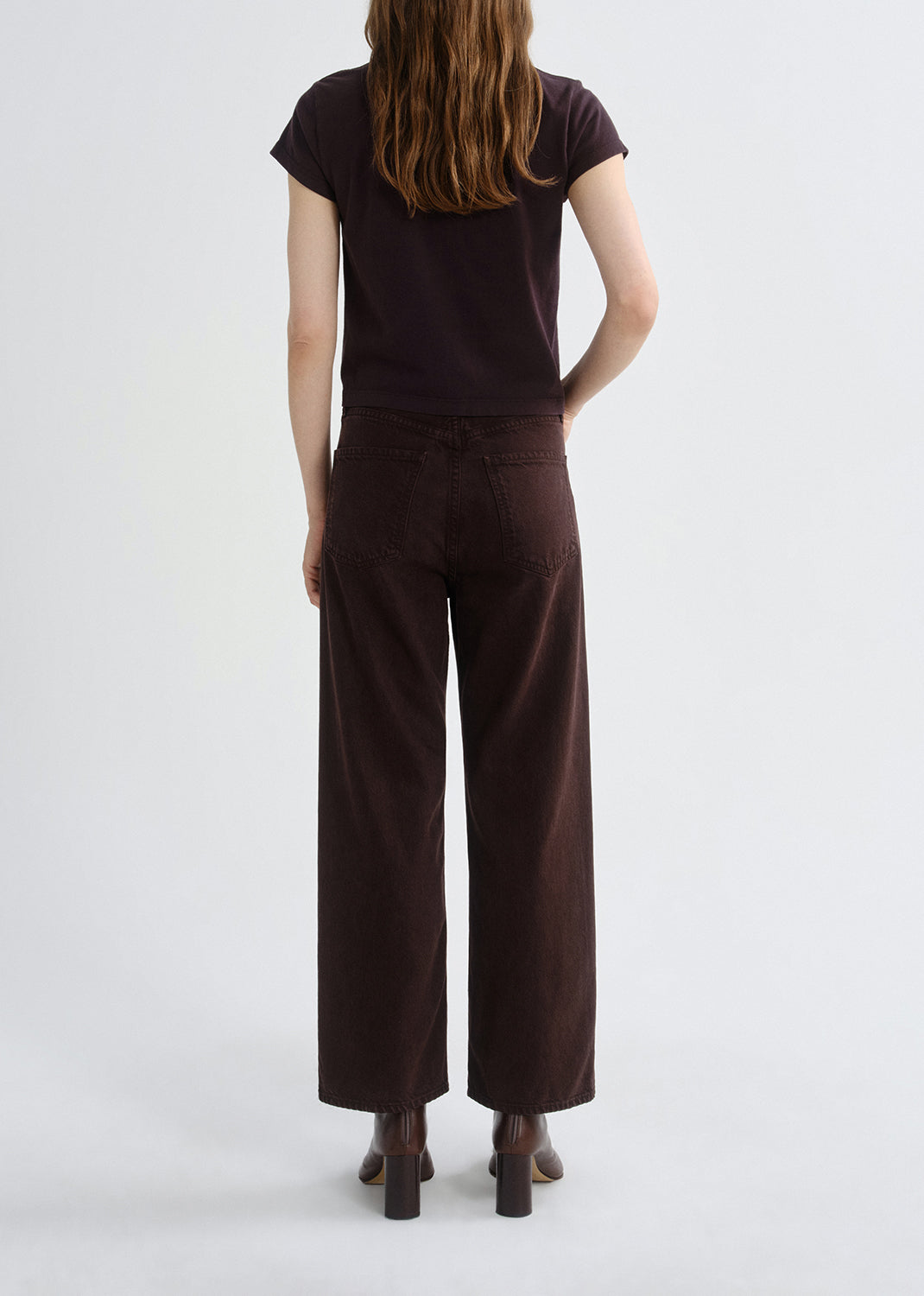 Person wearing a brown top and wide-leg pants on a grey background