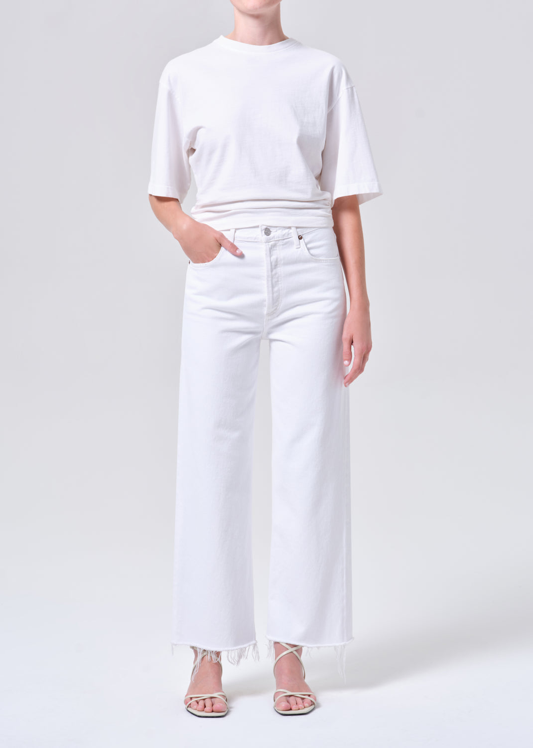Person wearing a white t-shirt and white wide-leg jeans on a light gray background