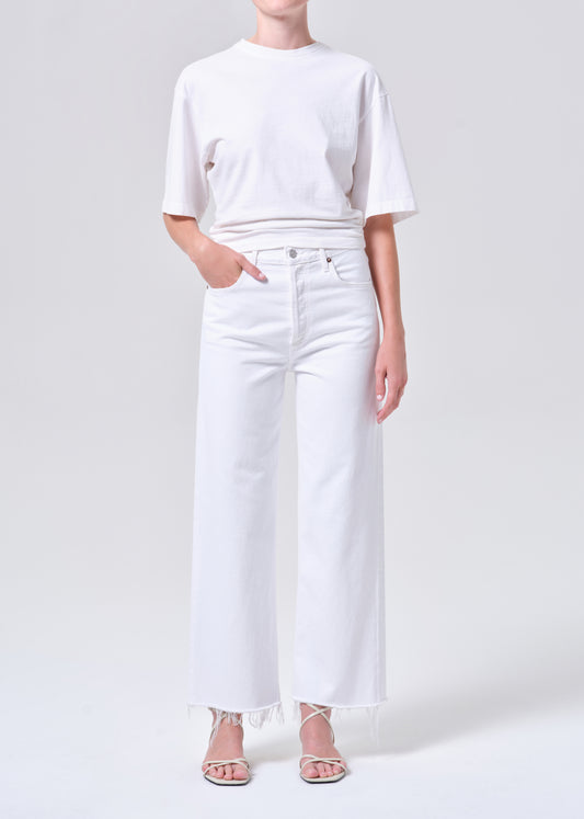 Person wearing a white t-shirt and white wide-leg jeans on a light gray background