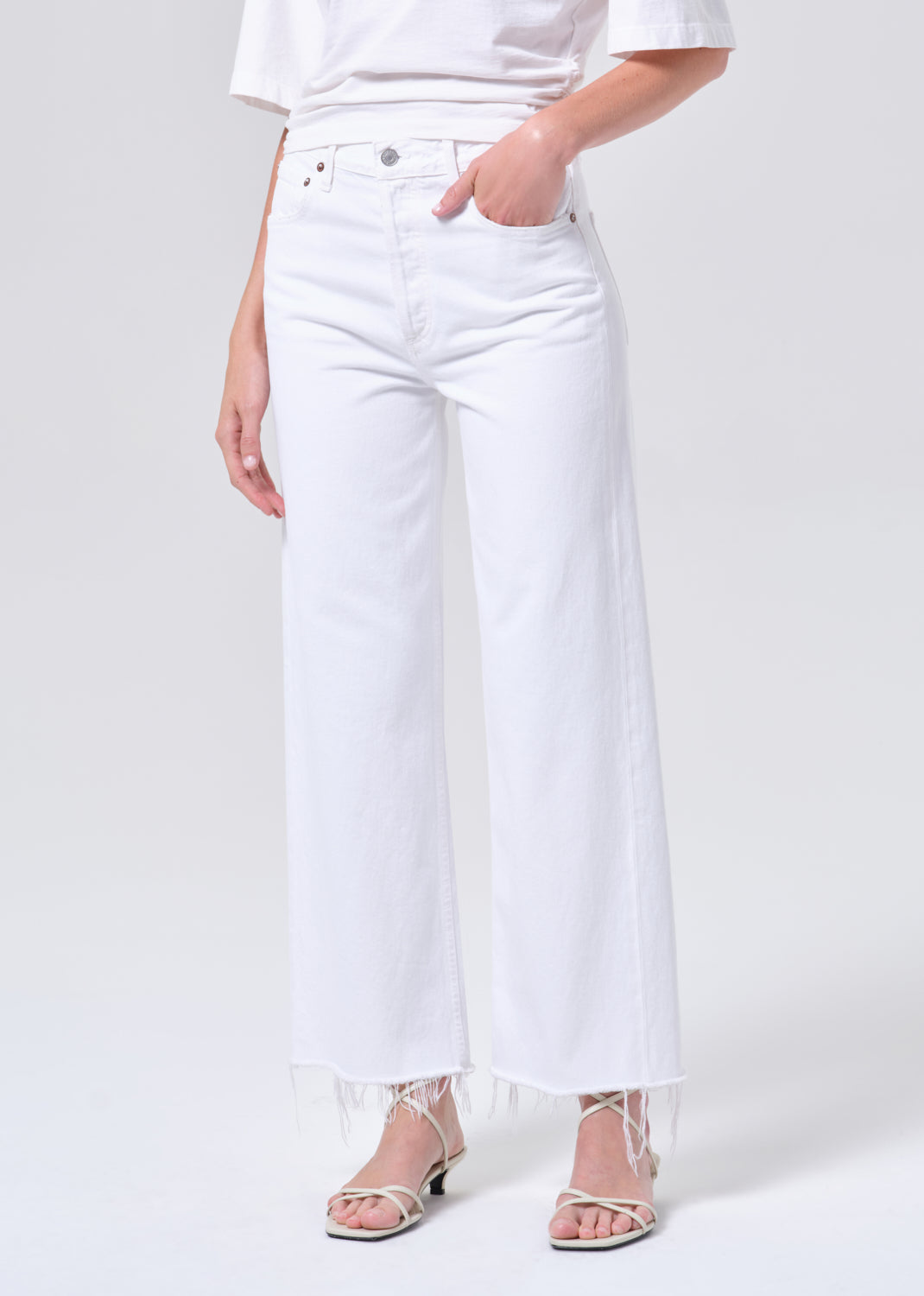 Person wearing white jeans and a white top on a plain background