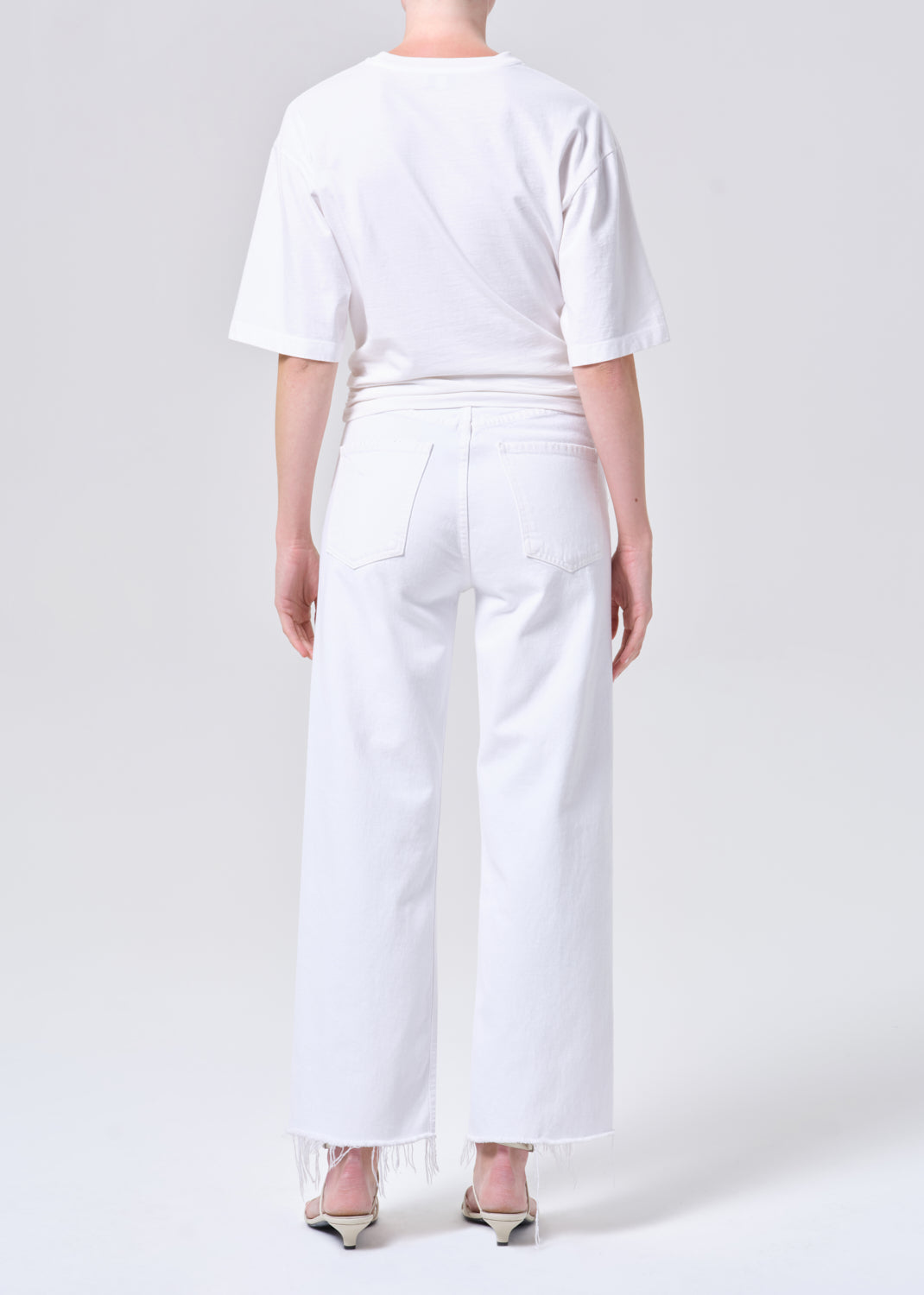 Person wearing a white t-shirt and white pants on a plain background