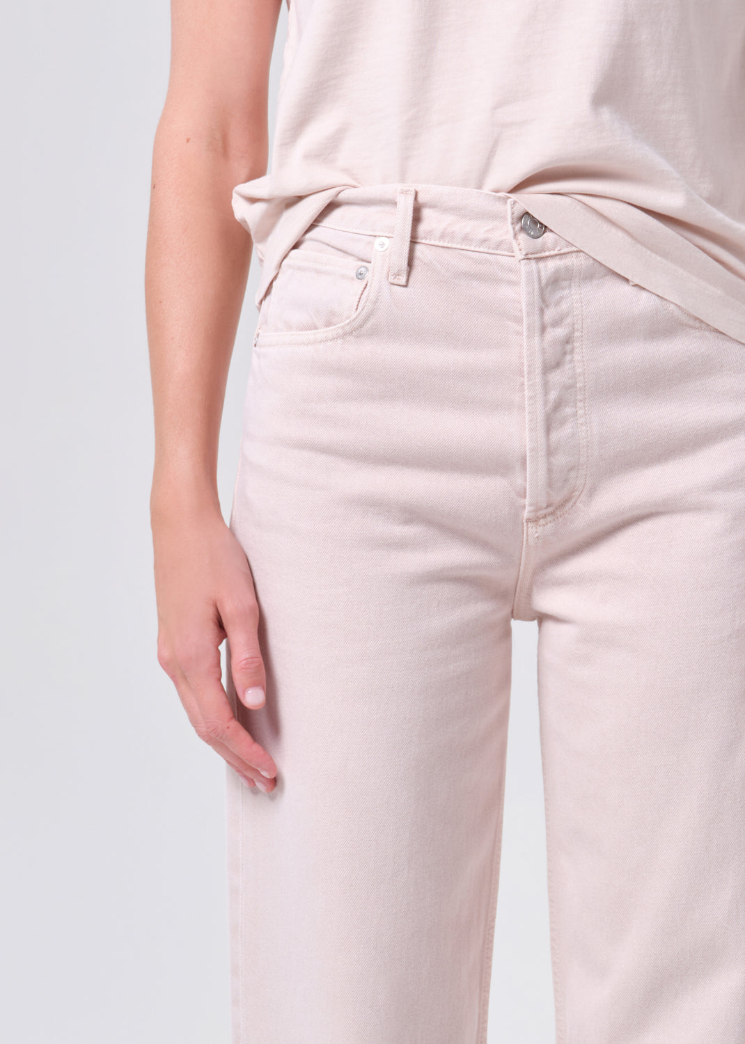 Light pink jeans worn by a person on a light gray background