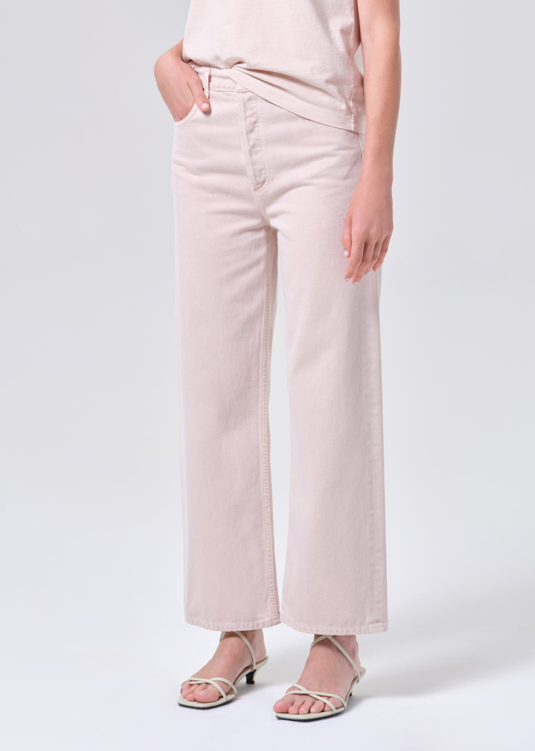 Person wearing light pink wide-leg jeans on a white background