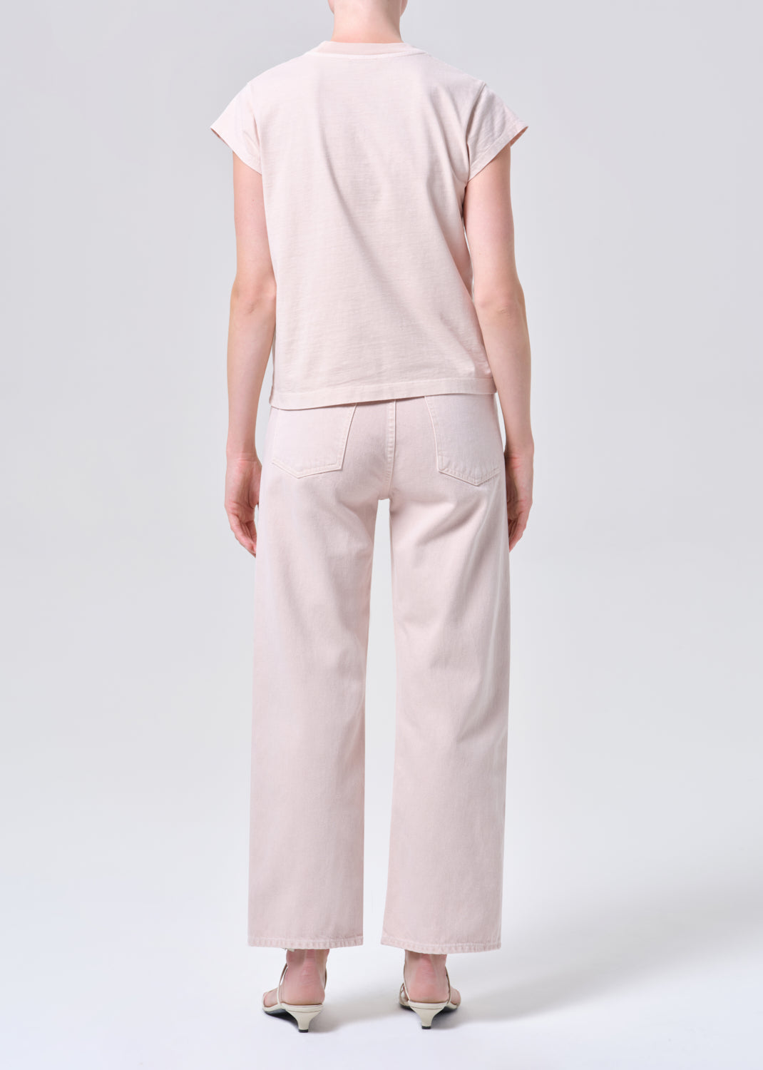 Person wearing a light pink t-shirt and pants on a white background