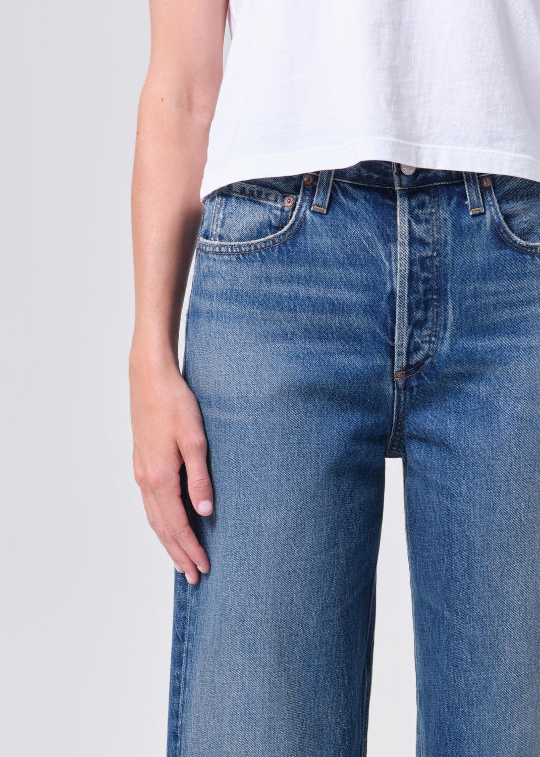 Blue jeans worn by a person on a light gray background