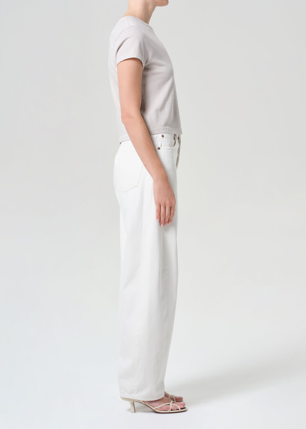 Person wearing a light gray t-shirt and white pants on a plain background