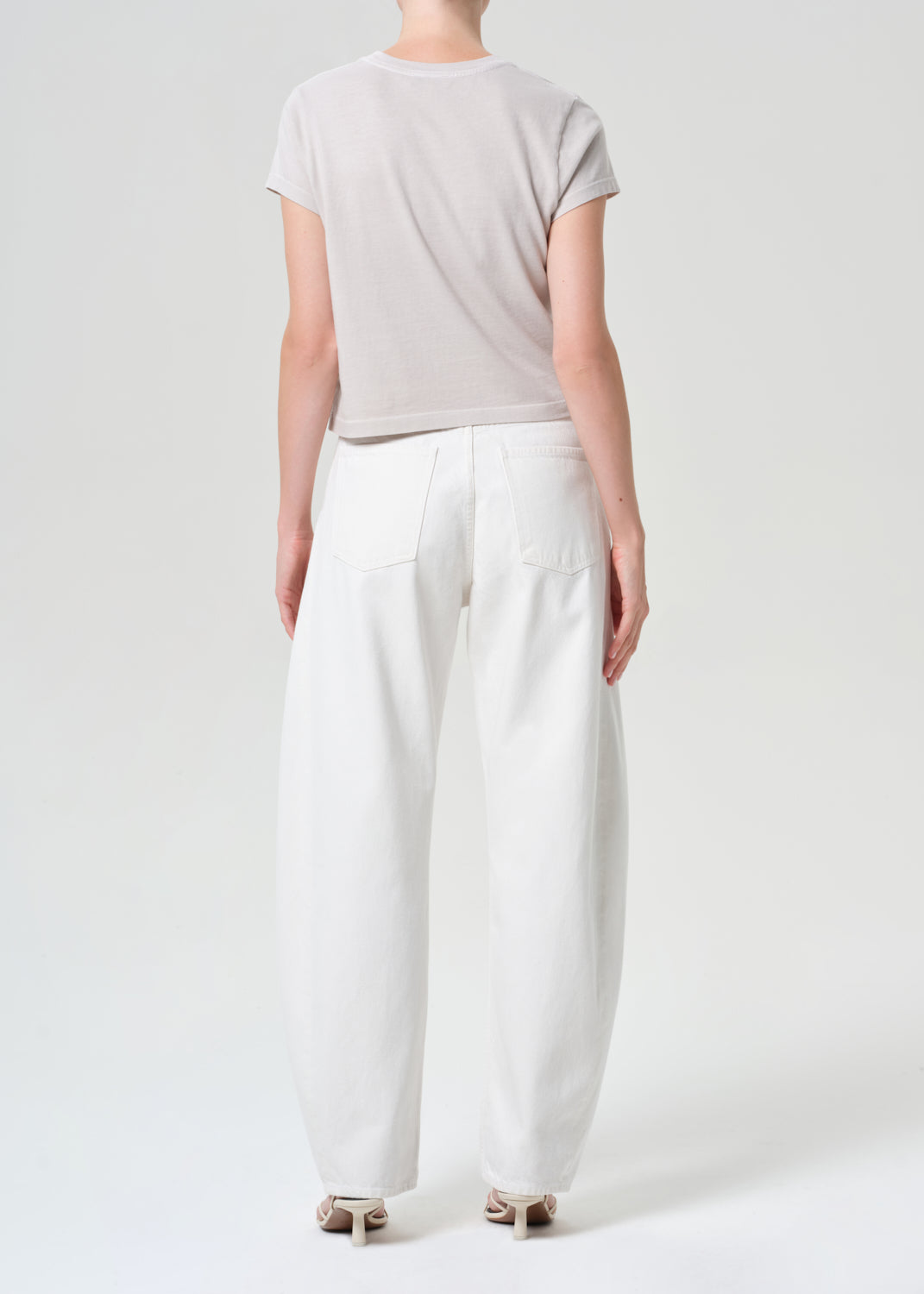 Person wearing a light gray t-shirt and white pants on a plain background