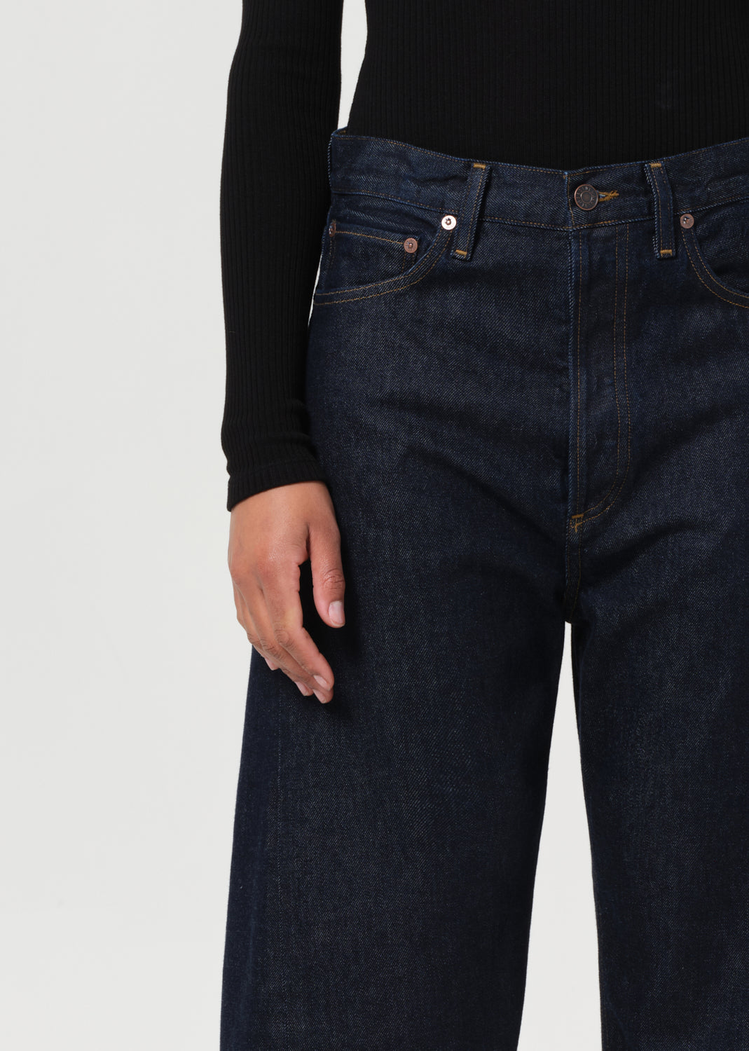 Dark blue jeans worn by a person on a light gray background