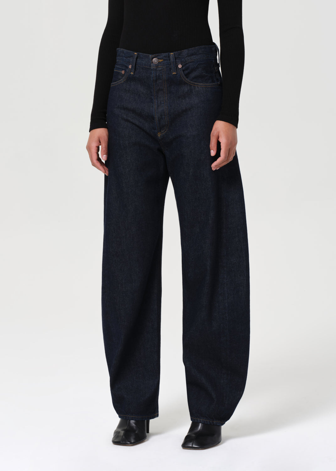 Person wearing dark blue jeans and black shoes on a white background