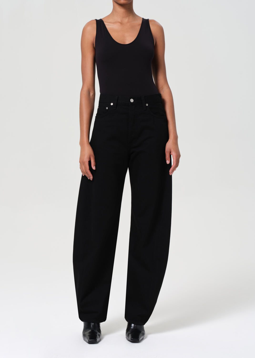 Person wearing a black sleeveless top and black pants on a white background