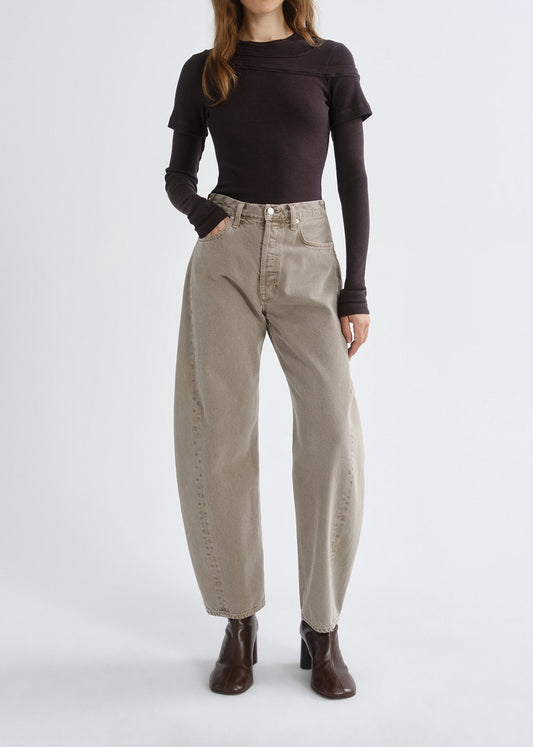 Person wearing a dark long-sleeve top and beige pants on a grey background