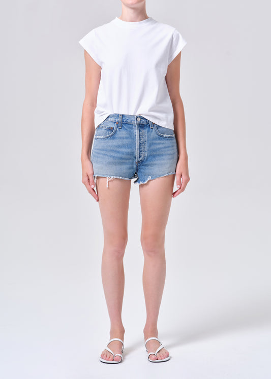 Person wearing a white t-shirt and light blue denim shorts on a plain background