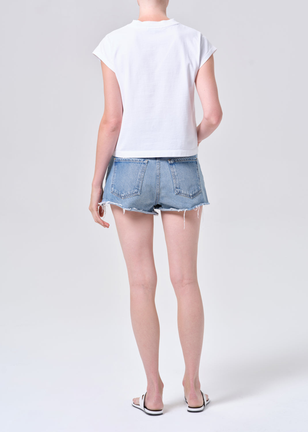 Person wearing a white t-shirt and denim shorts on a plain background