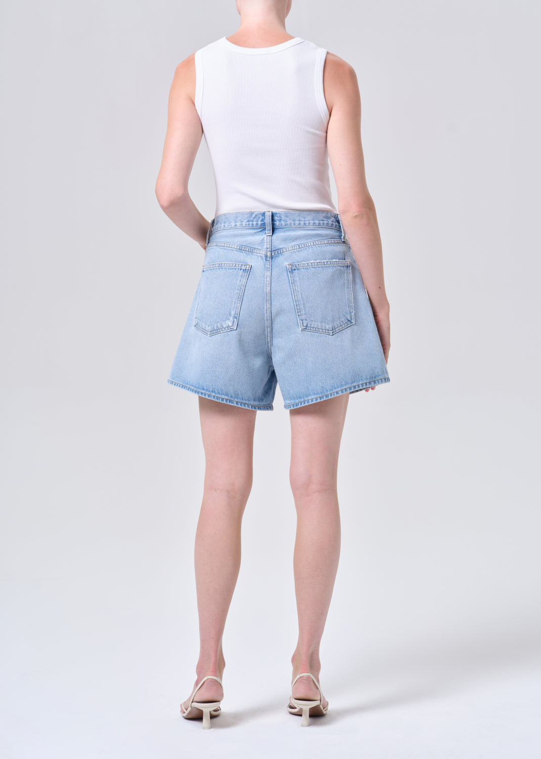 Person wearing light blue denim shorts on a white background