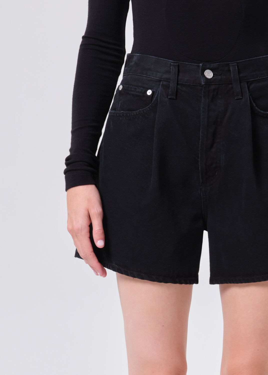 Person wearing a black denim skirt on a plain background