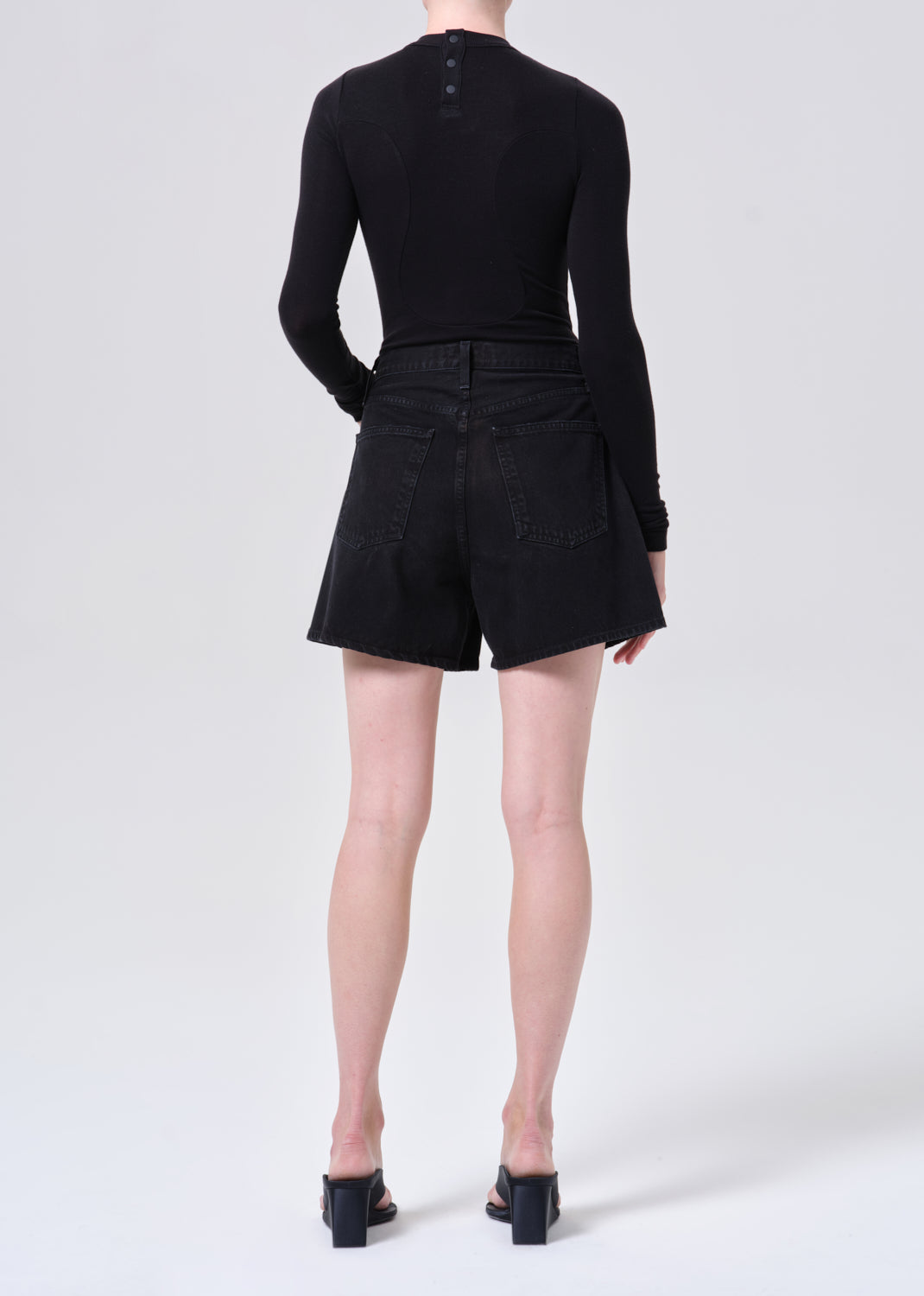 Person wearing a black outfit with shorts on a white background