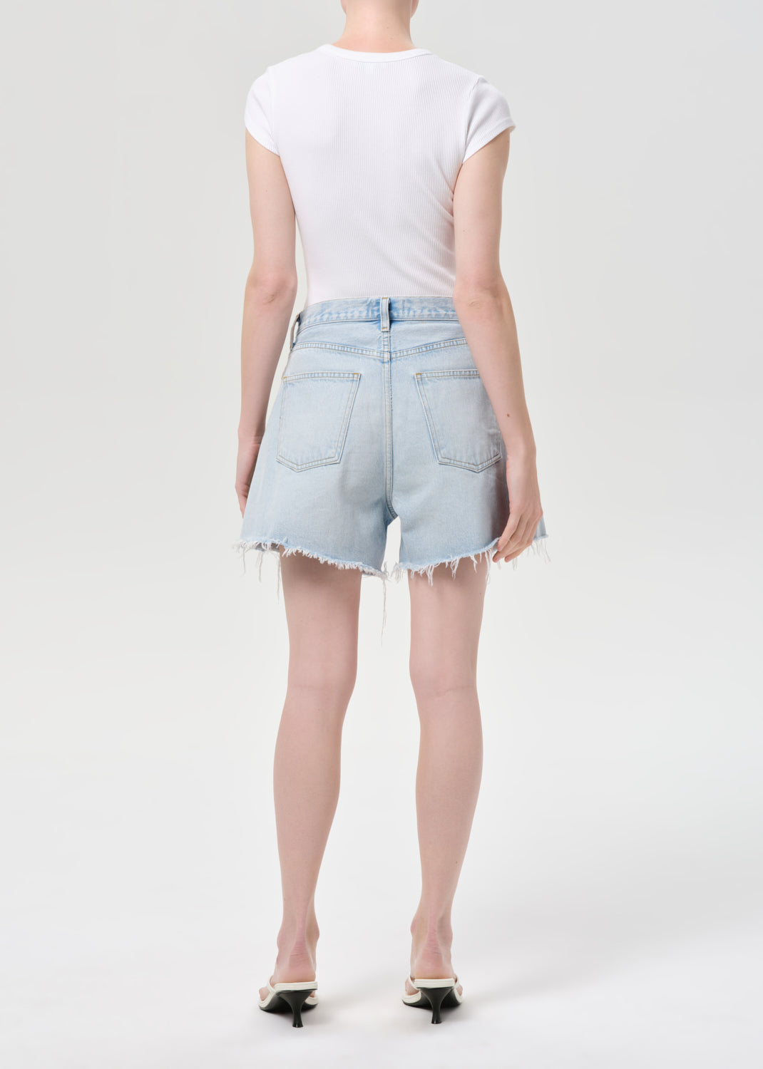 Person wearing a white t-shirt and light blue denim shorts on a white background