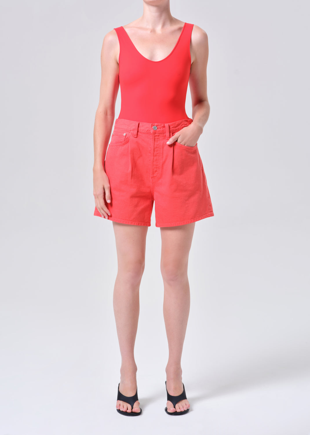 Person wearing a red tank top and shorts on a white background