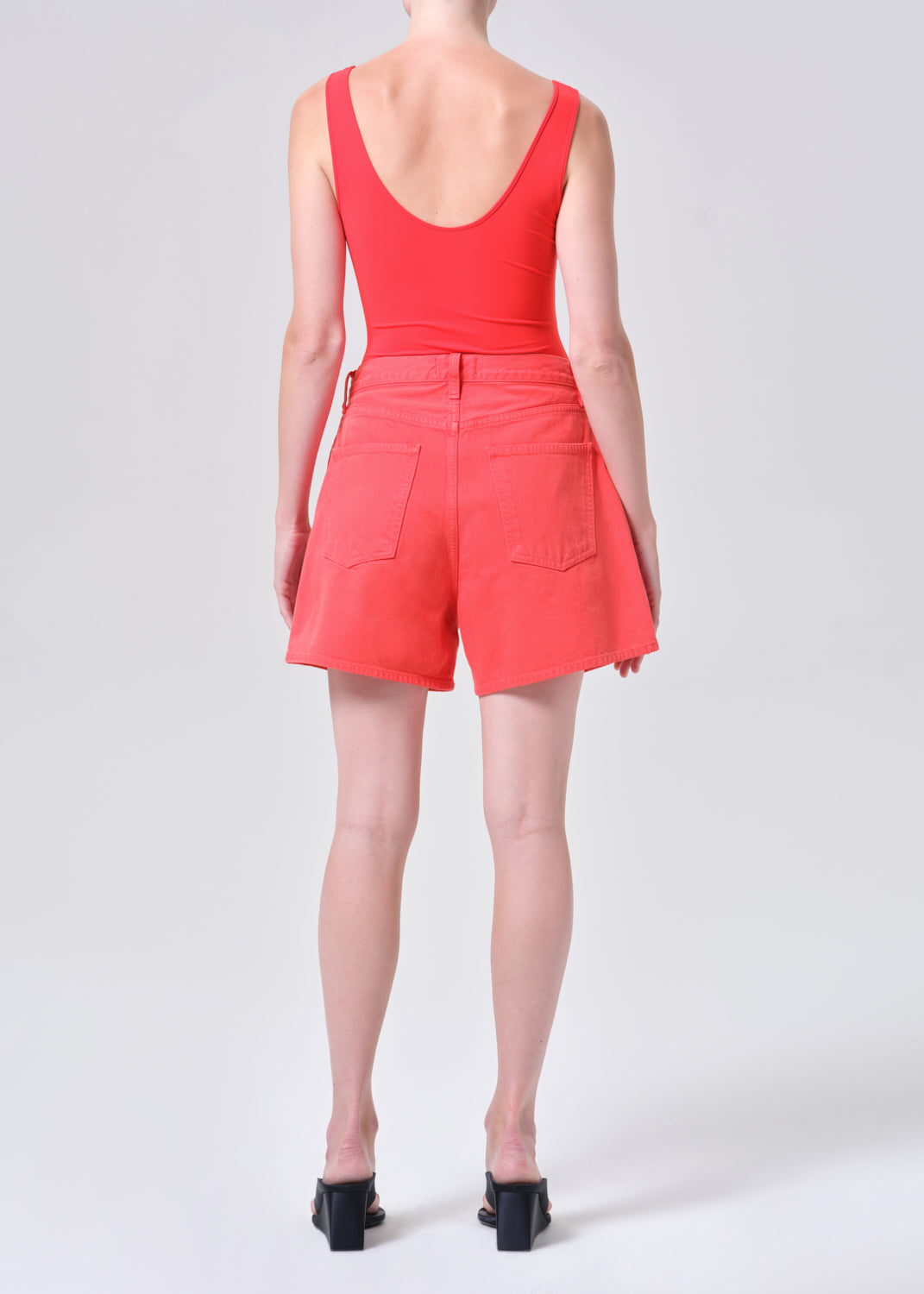 Person wearing a red sleeveless top and shorts on a white background