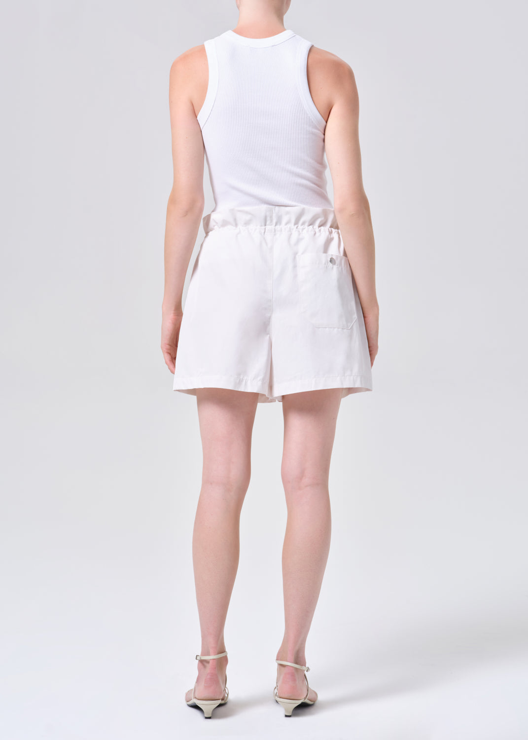 Person wearing a white sleeveless top and shorts on a white background