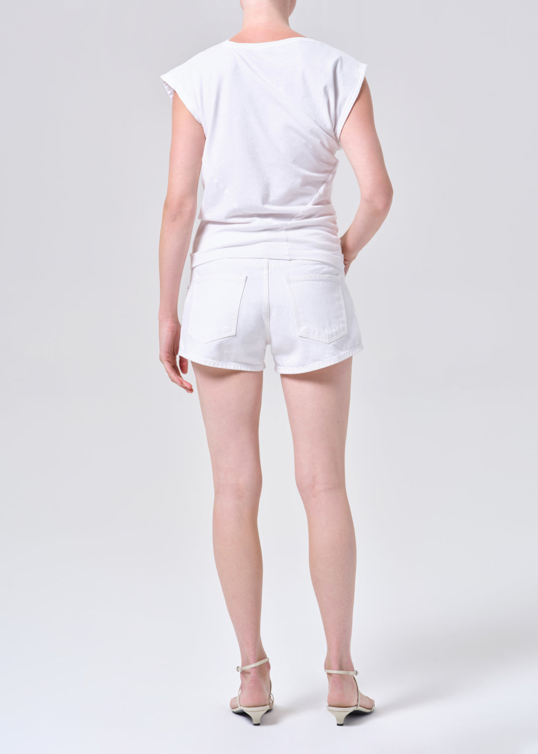 Person wearing a white t-shirt and shorts on a plain background