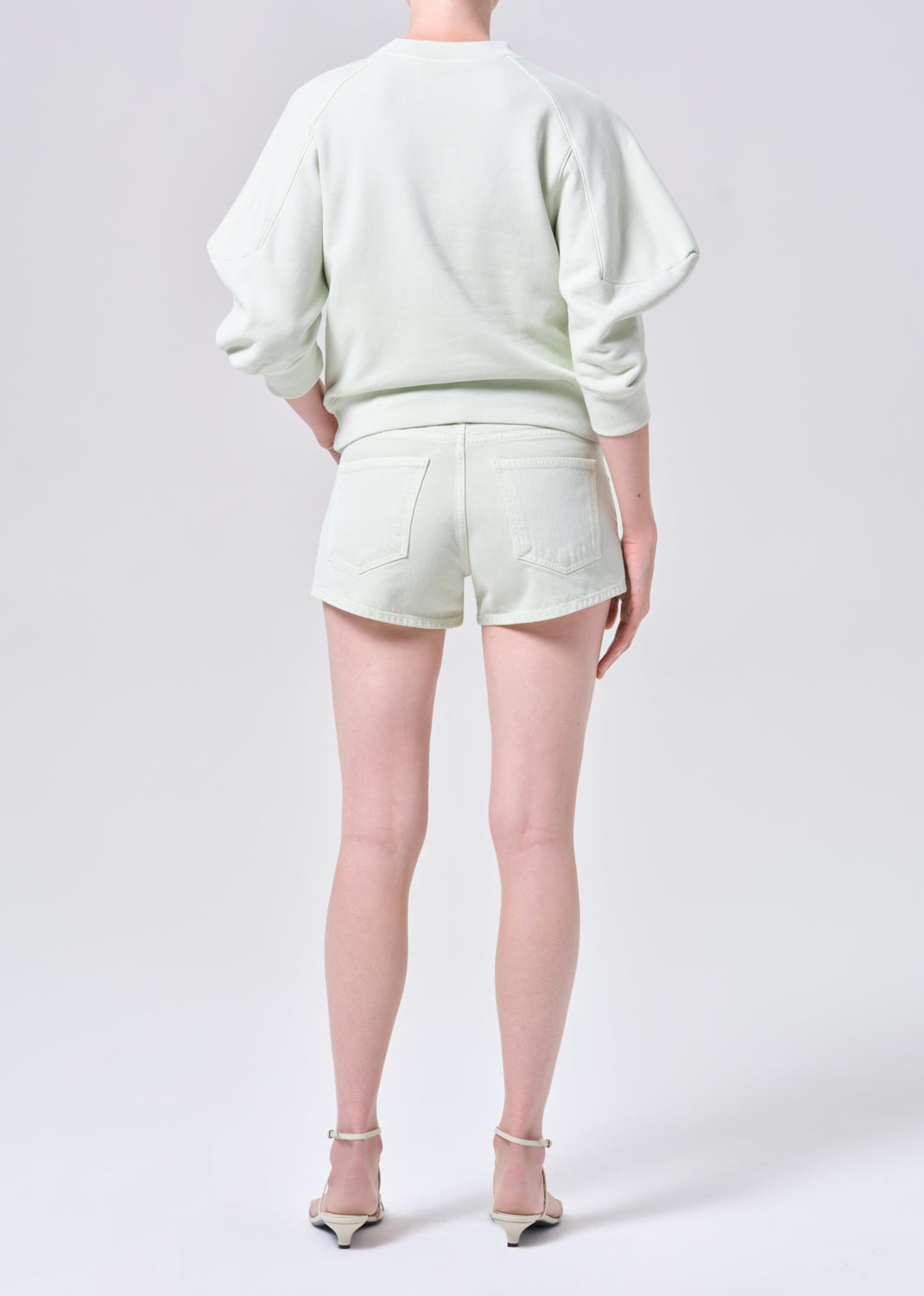 Person wearing a light green outfit with shorts on a white background