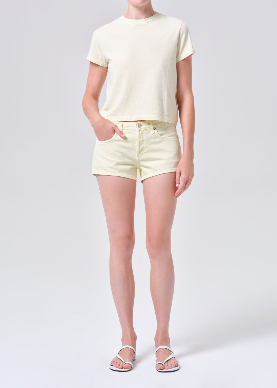 Person wearing a light yellow t-shirt and shorts on a white background