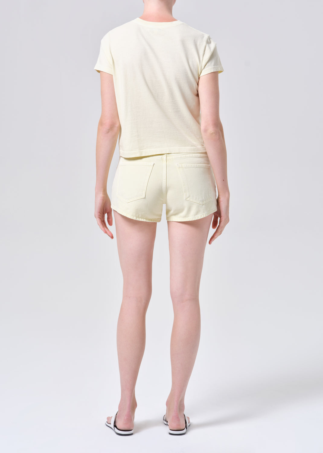 Person wearing a light yellow t-shirt and shorts on a white background