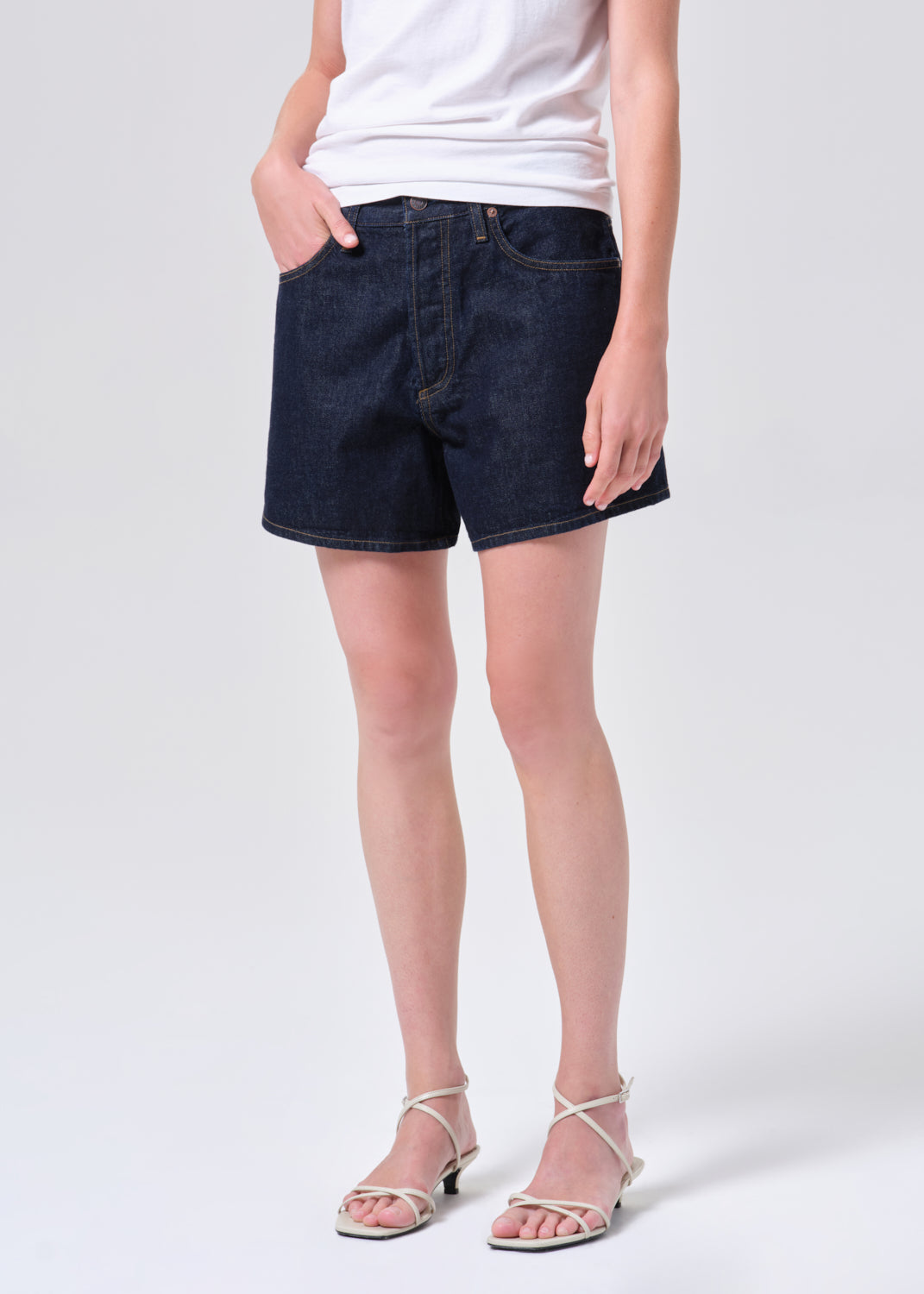 Person wearing dark blue denim shorts on a white background