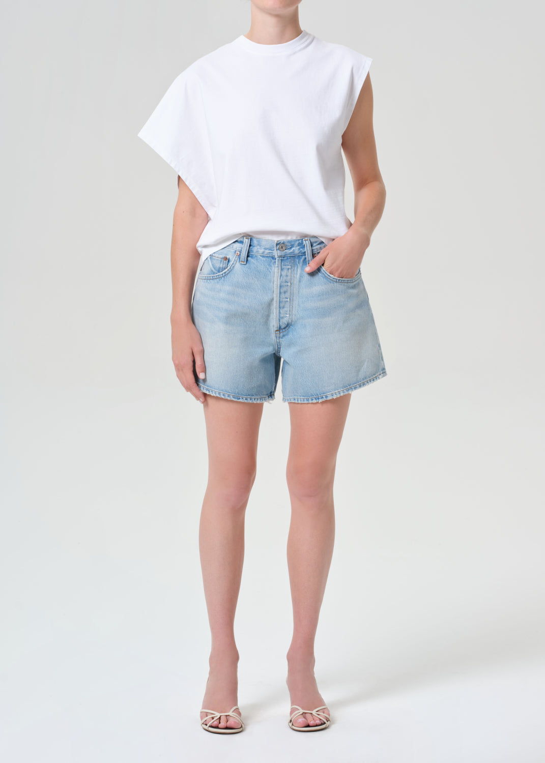 Person wearing a white t-shirt and light blue denim shorts on a white background