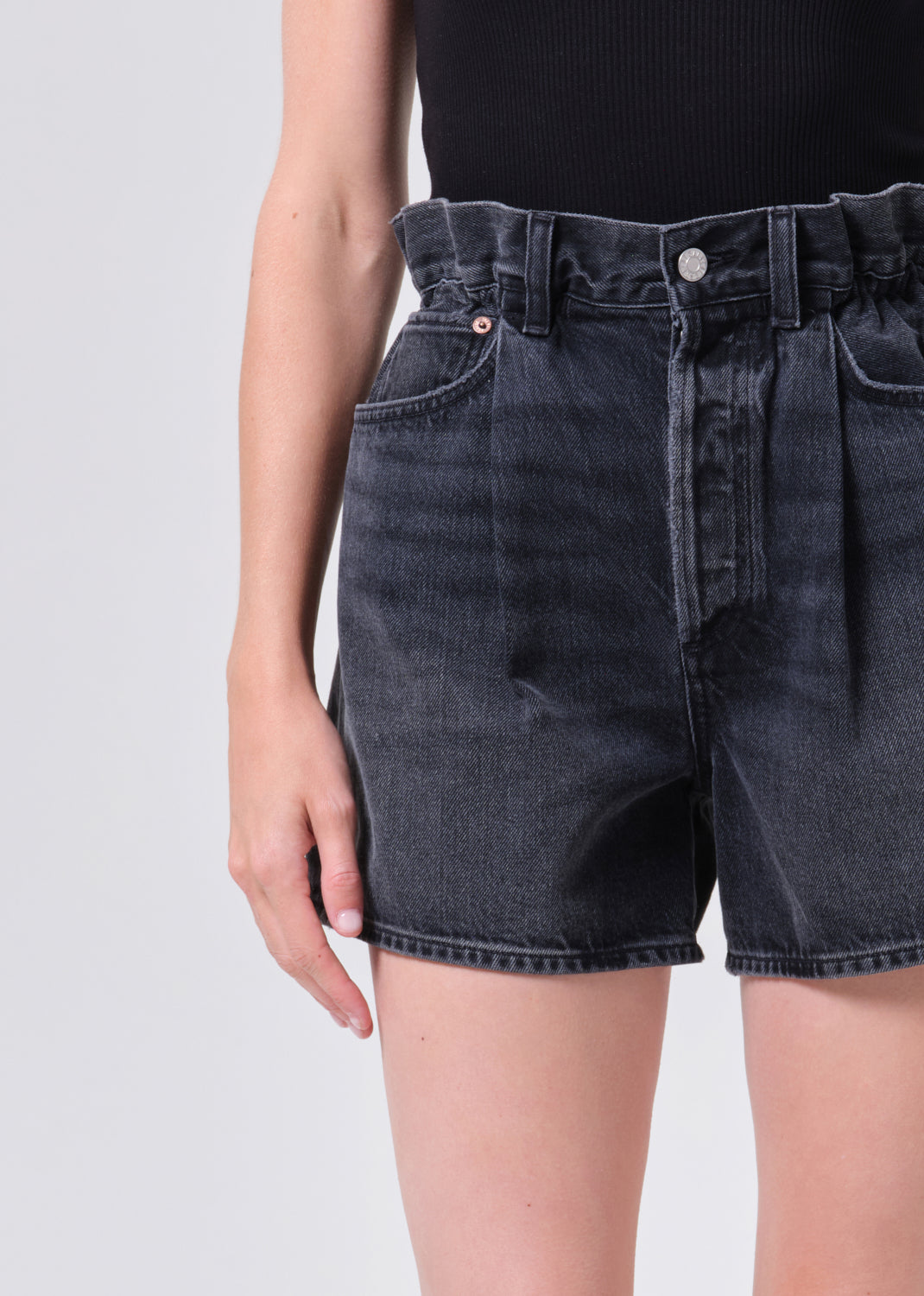Black denim shorts worn by a person on a light gray background