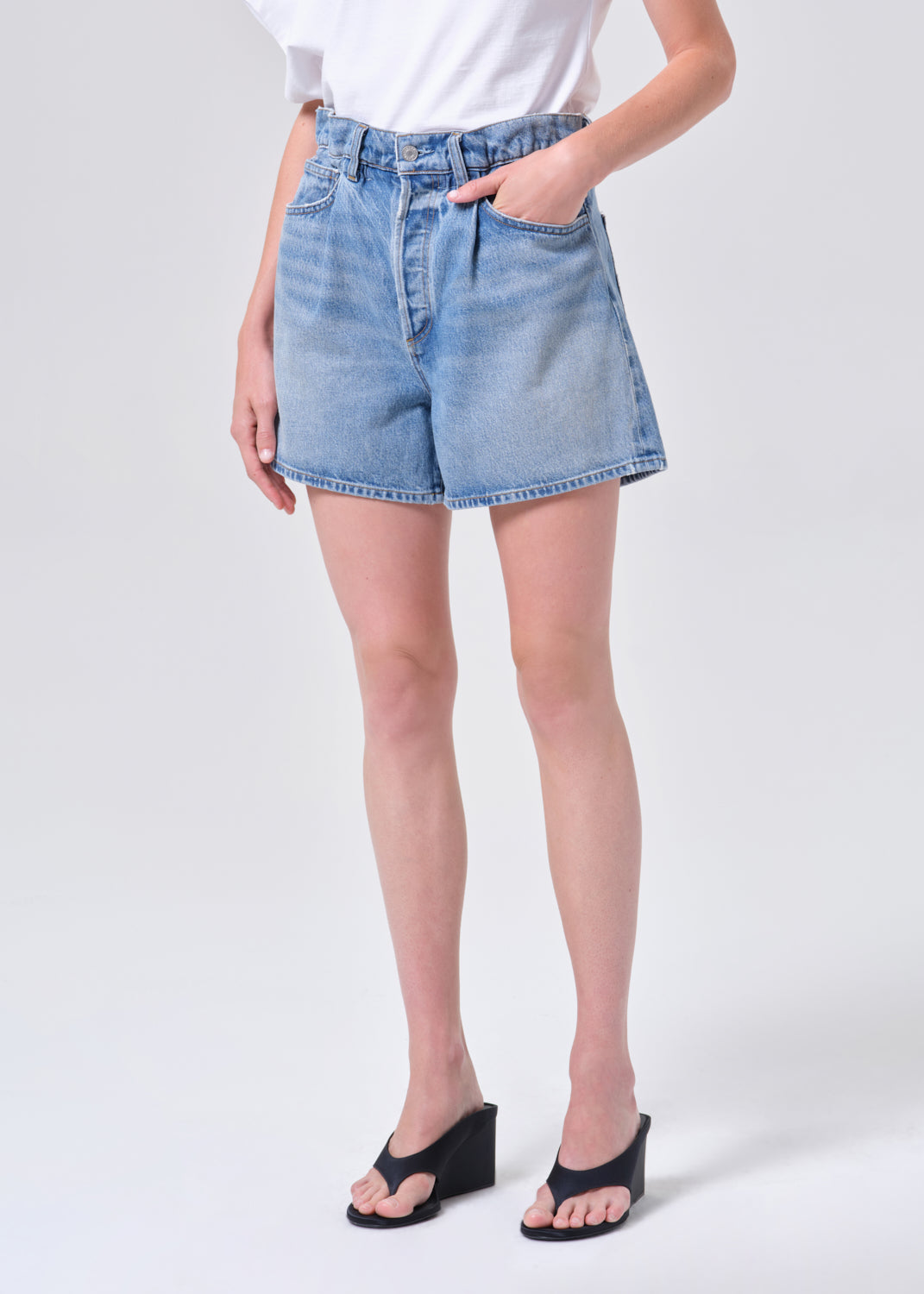 Person wearing light blue denim shorts on a white background
