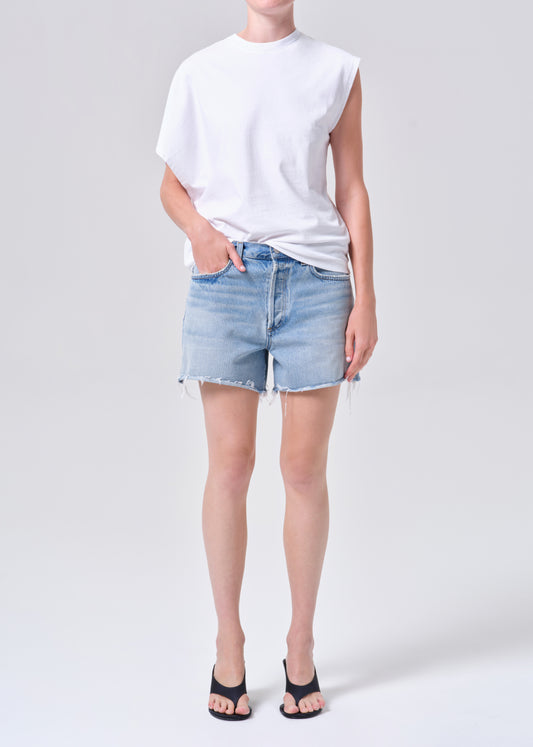 Person wearing a white t-shirt and light blue denim shorts on a plain background