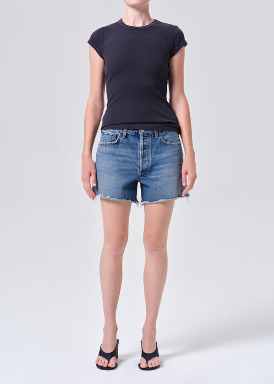 Person wearing a black t-shirt and denim shorts on a white background