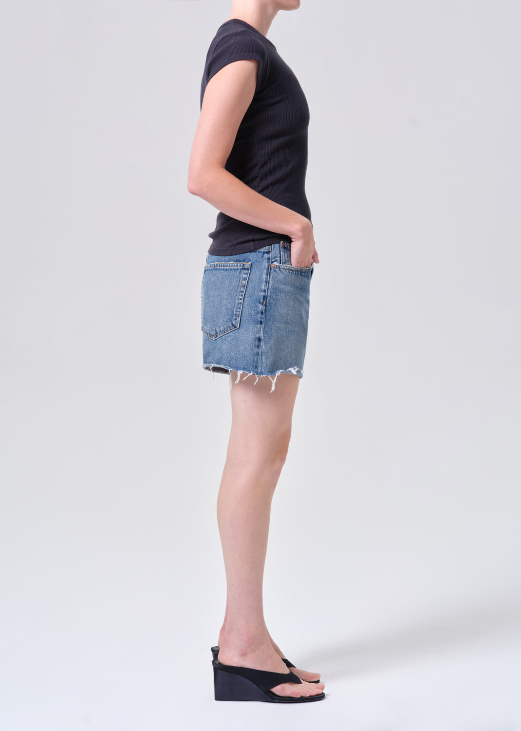Person wearing a black t-shirt and denim skirt on a white background