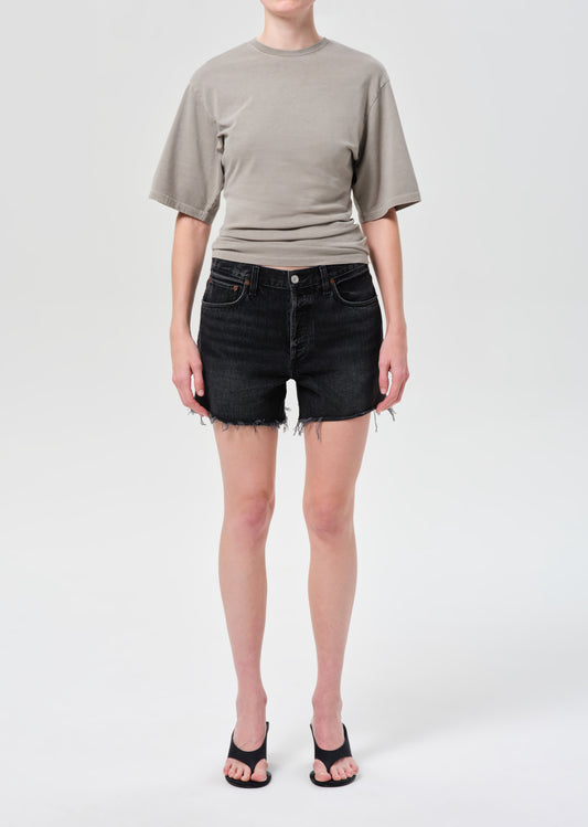Person wearing a gray t-shirt and black denim shorts on a white background