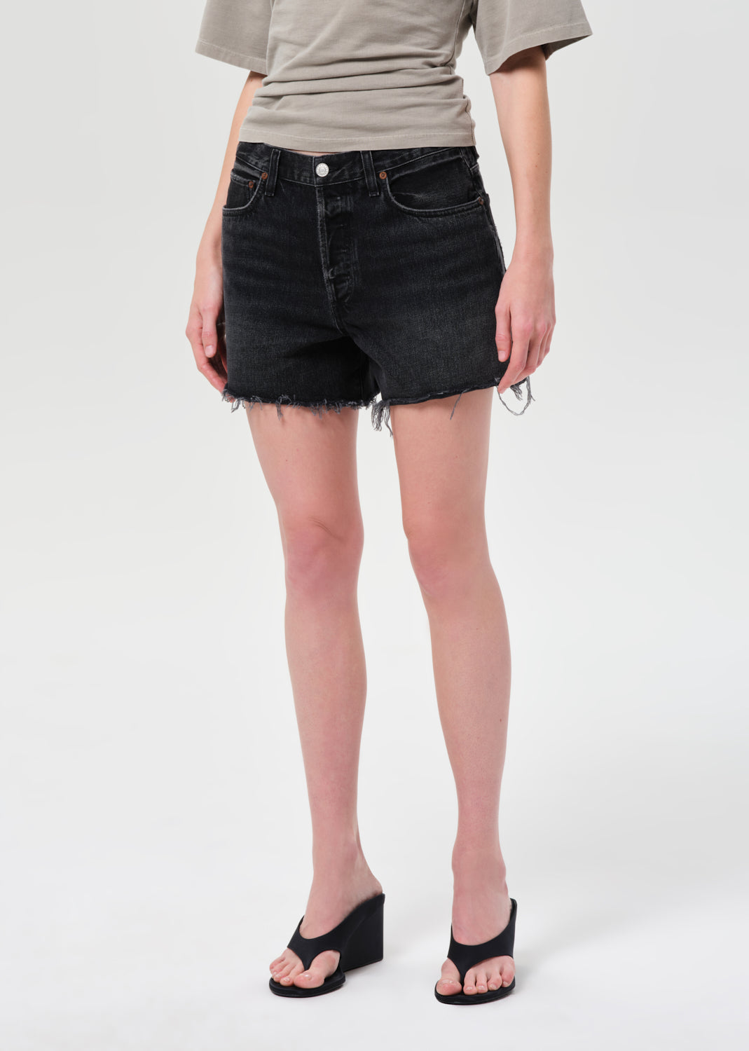 Person wearing black denim shorts on a white background