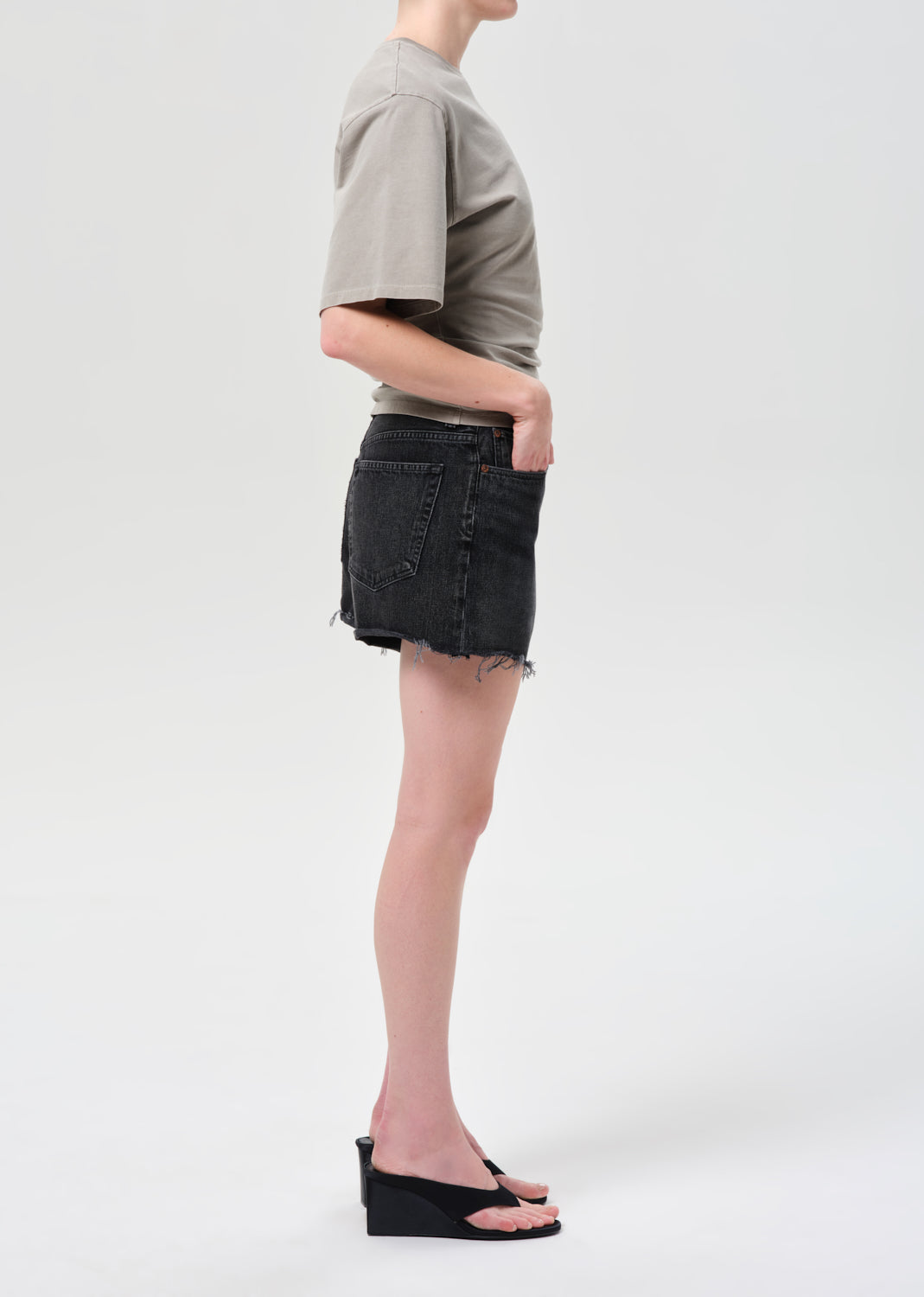 Person wearing a gray t-shirt and black denim shorts on a white background