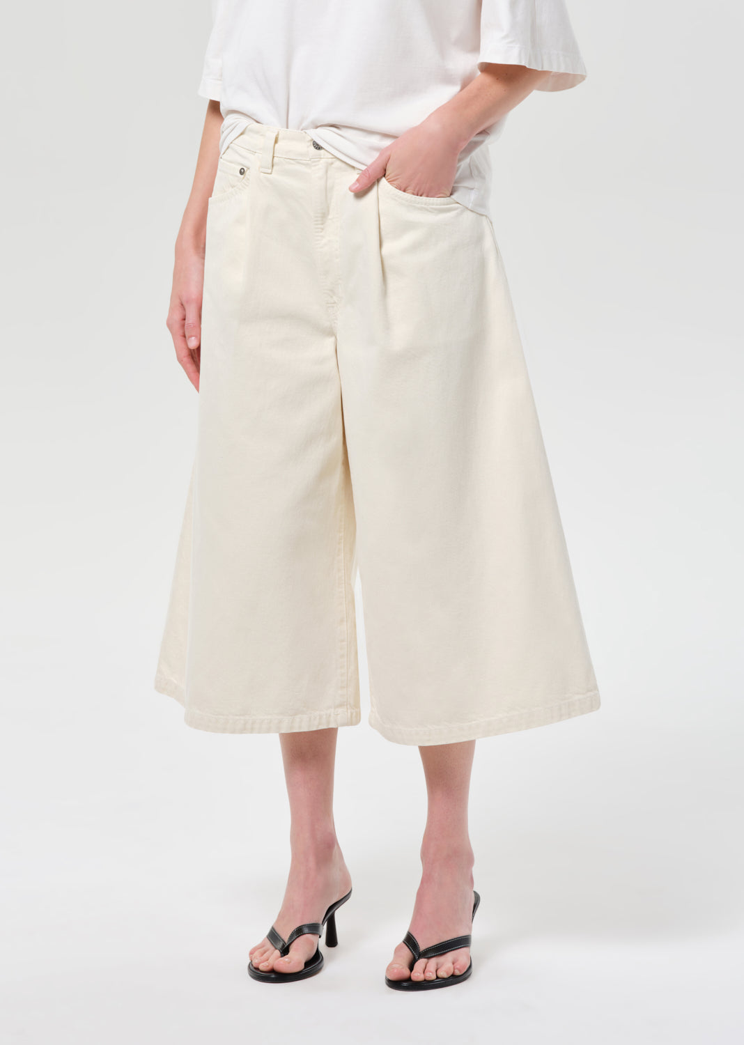 Person wearing white wide-leg pants and a white shirt on a plain background