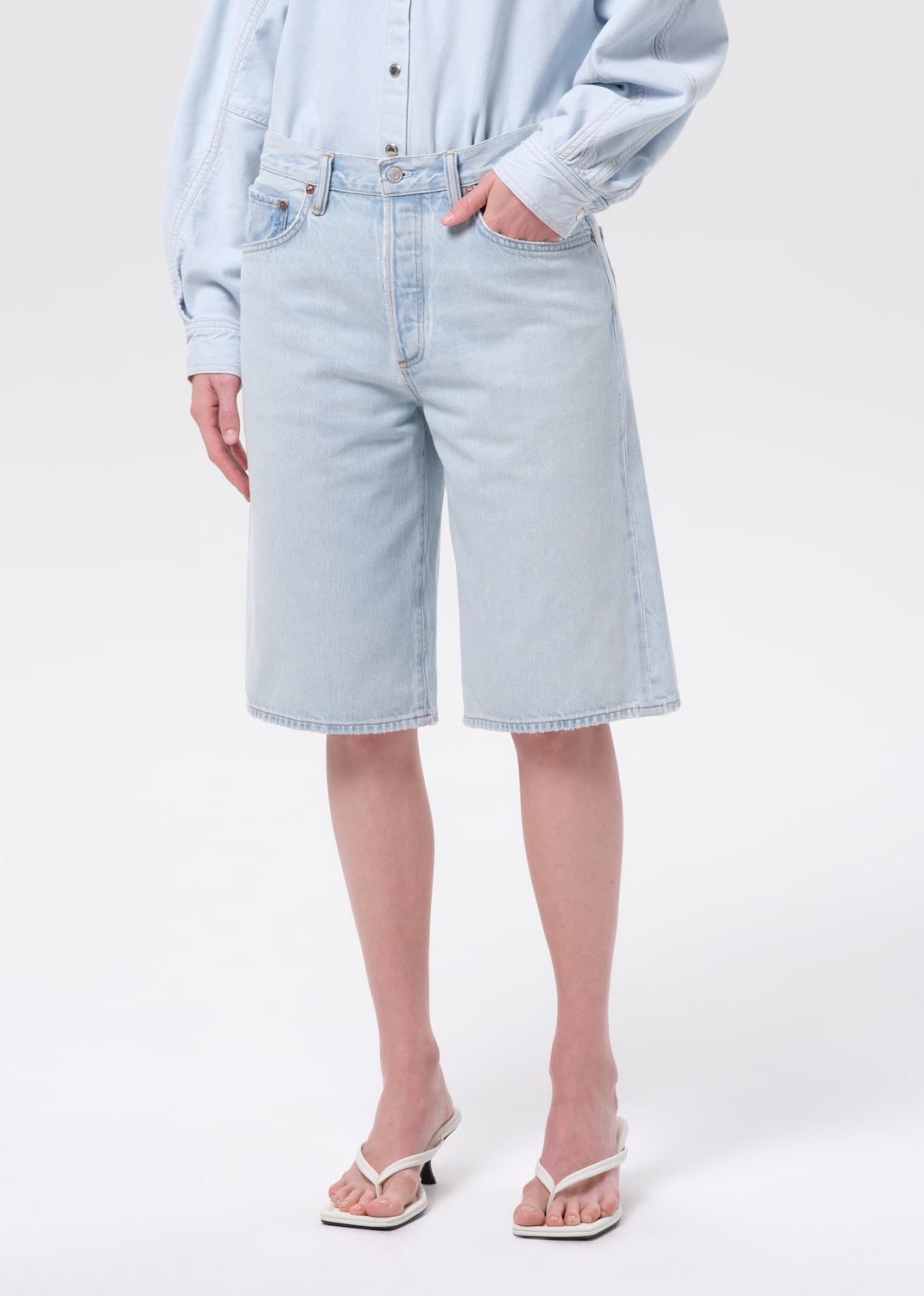 Person wearing light blue denim shorts and a light blue shirt on a white background