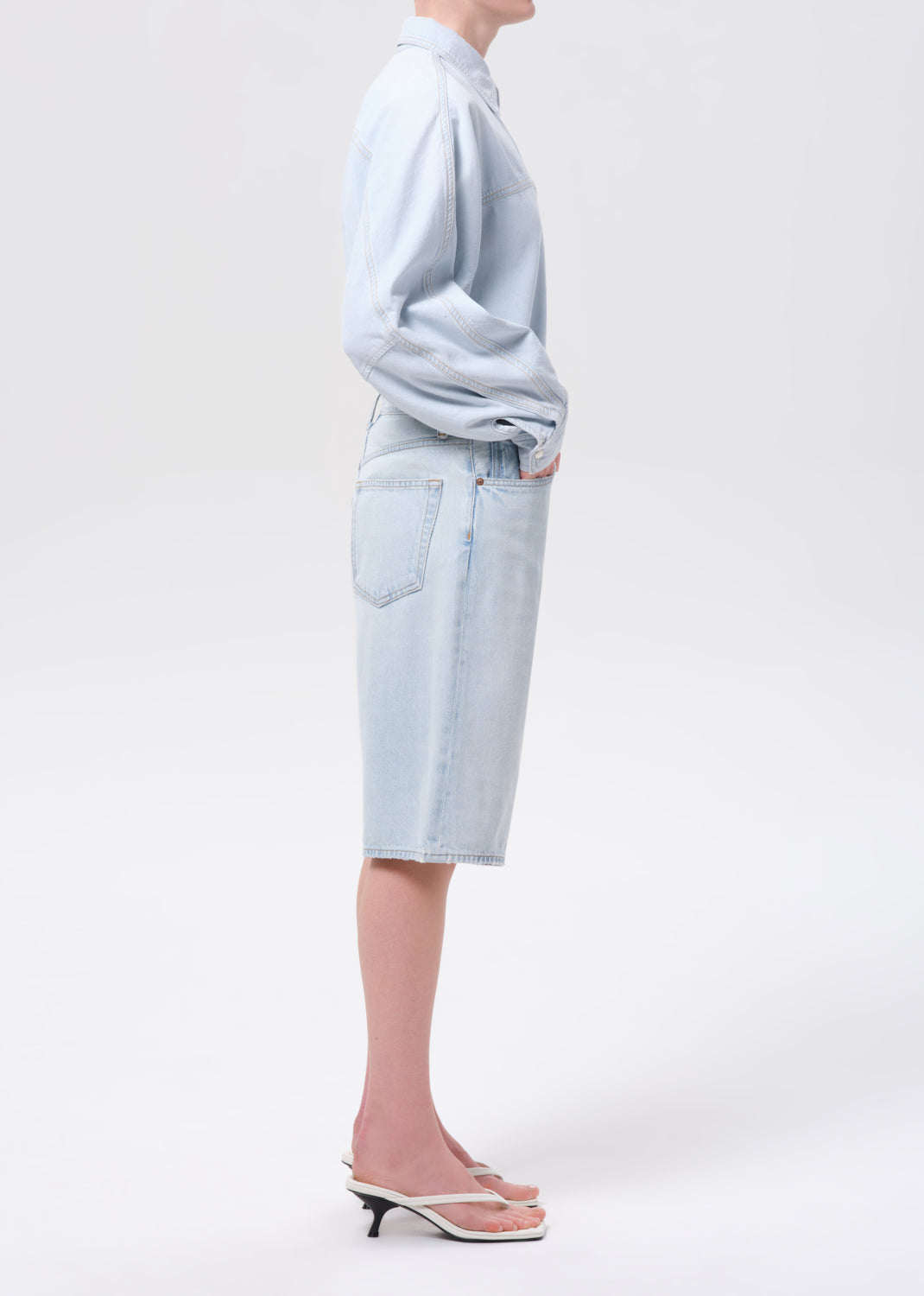 Person wearing a light blue outfit with a skirt on a white background