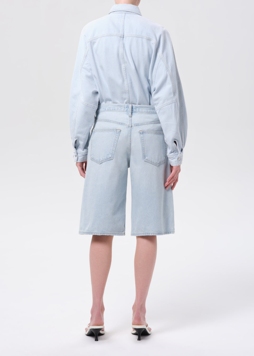 Person wearing a light blue denim outfit on a white background