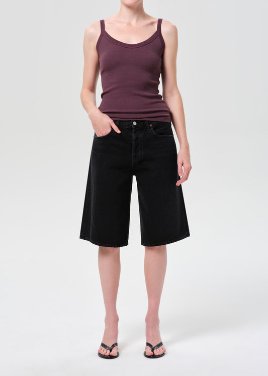 Person wearing a purple tank top and black shorts on a white background