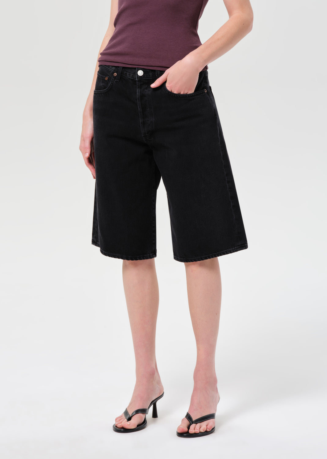 Person wearing black denim shorts on a white background